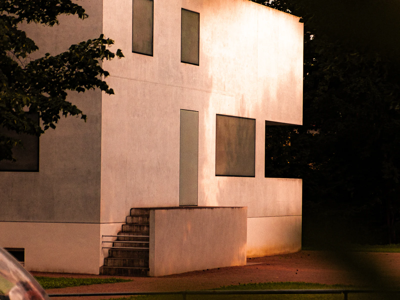 Heller Neubau mit klarer Fassadengliederung zwischen Bäumen