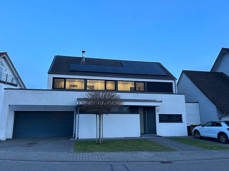 Modernes weißes Wohnhaus mit Photovoltaikmodulen auf dem Dach