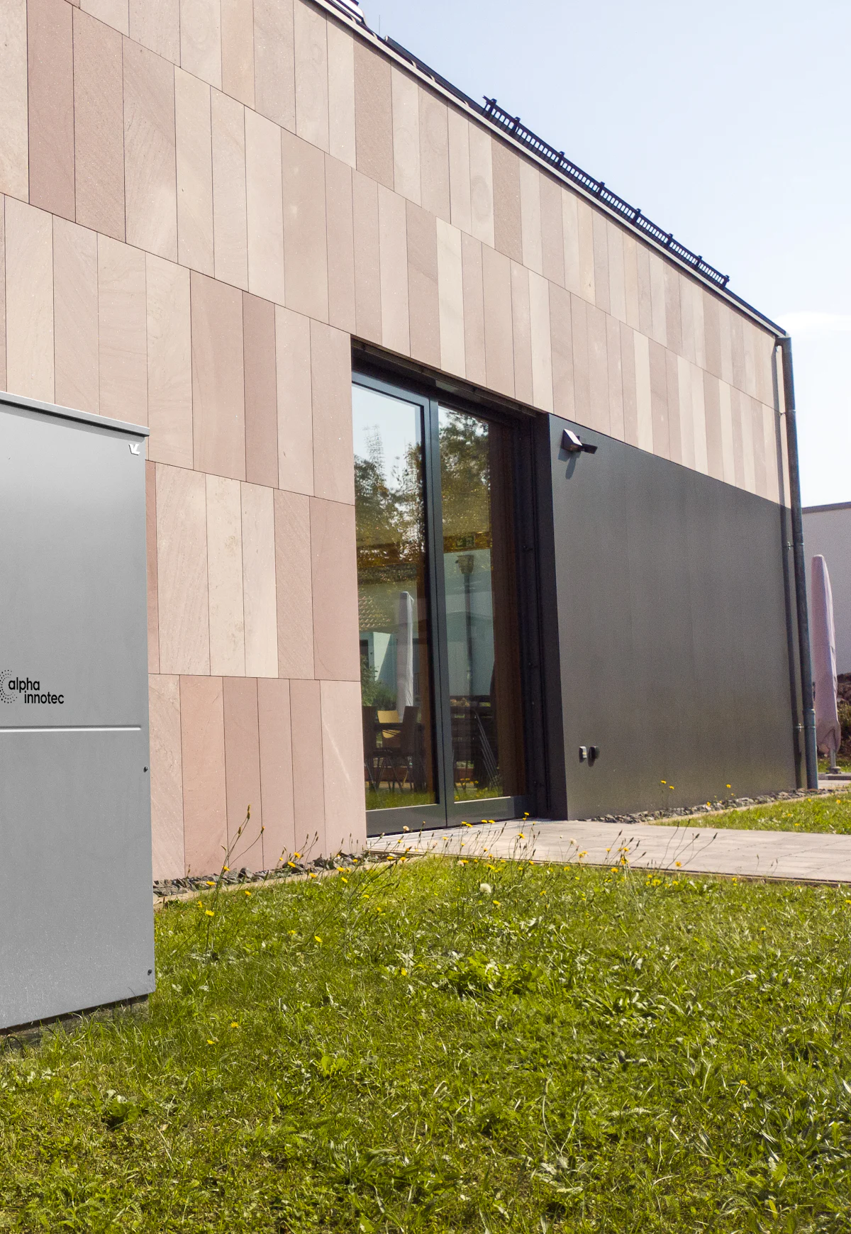 Wärmepumpe an der Außenwand eines modernen Wohnhauses